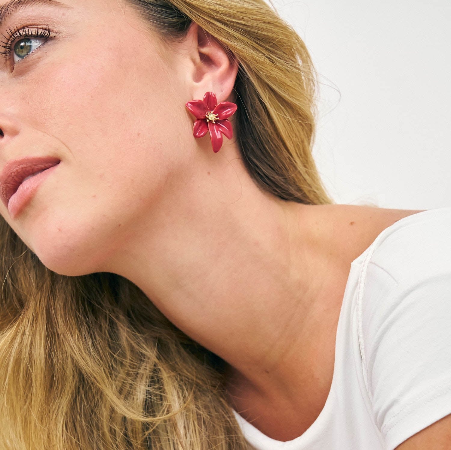 Girl wearing pink and gold hibiscus flower shaped earrings 